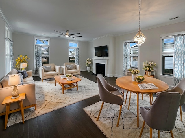 dining space featuring hardwood / wood-style flooring, ornamental molding, a healthy amount of sunlight, and ceiling fan with notable chandelier