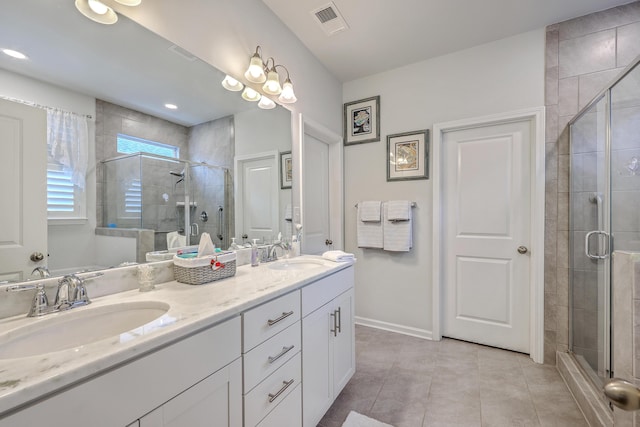 bathroom with a shower stall, double vanity, a sink, and visible vents