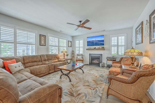 living area with visible vents, ceiling fan, and a fireplace with flush hearth