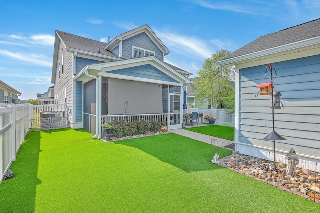 back of house with a yard, roof with shingles, a fenced backyard, and a sunroom