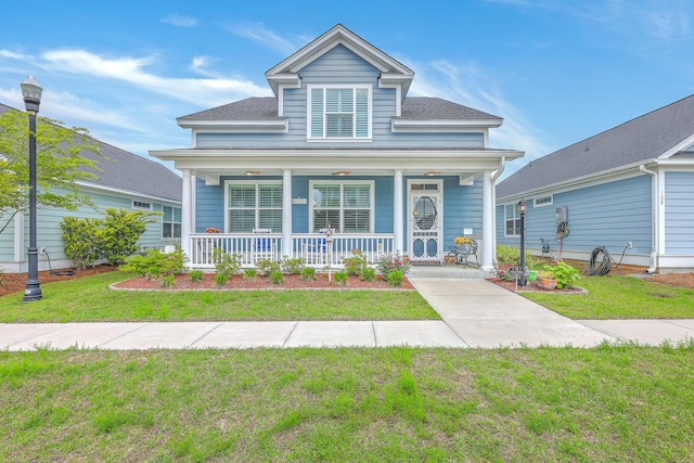 bungalow-style house with roof with shingles, covered porch, and a front lawn
