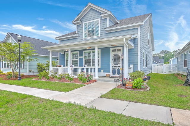 bungalow with a porch, a shingled roof, fence, and a front lawn