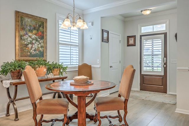 dining area featuring crown molding, light wood-style flooring, a notable chandelier, and baseboards