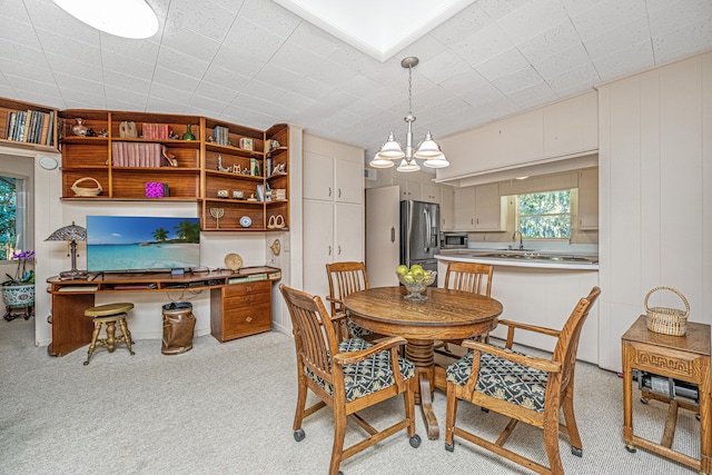 dining room featuring light carpet and a chandelier