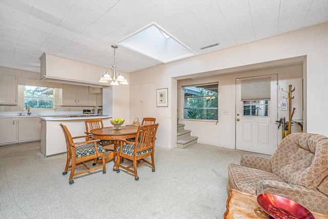 carpeted dining space with a skylight, sink, and a chandelier