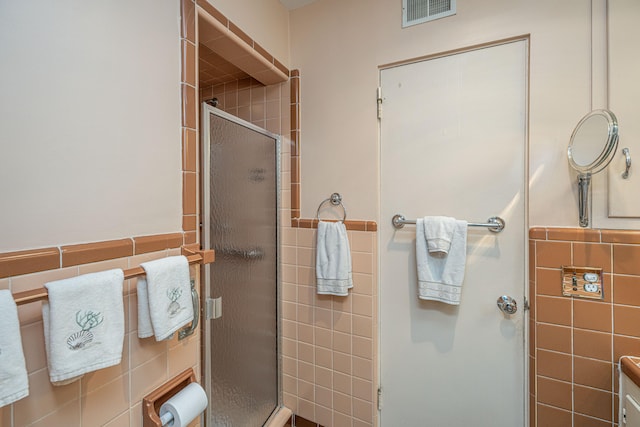 bathroom with a shower with shower door and tile walls