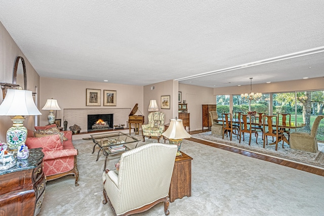 living room with a brick fireplace, a notable chandelier, a textured ceiling, and light hardwood / wood-style flooring