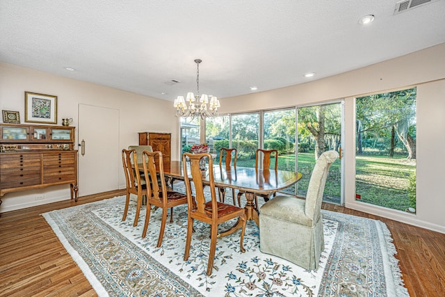 dining space with wood-type flooring, a textured ceiling, and a chandelier