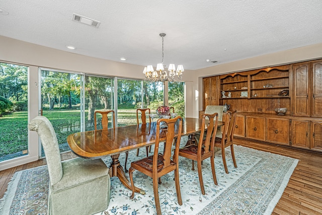 dining space with light hardwood / wood-style flooring, a chandelier, and a textured ceiling