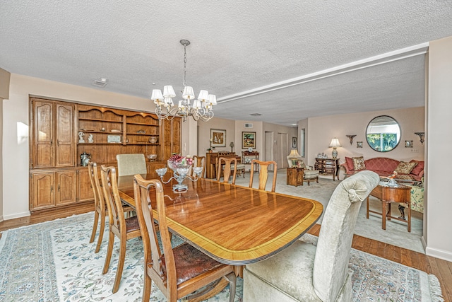 dining space featuring a textured ceiling, light wood-type flooring, and a notable chandelier