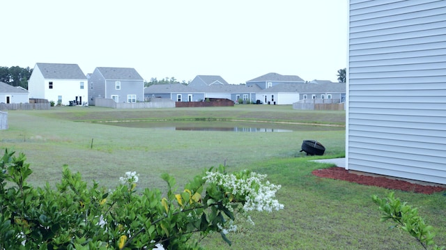 view of green lawn with a residential view and a water view
