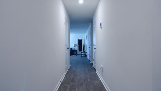 hall featuring dark wood-style flooring and baseboards