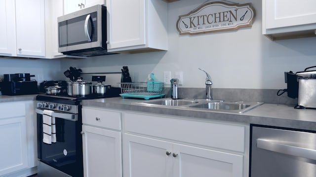 kitchen with stainless steel appliances, a sink, and white cabinets