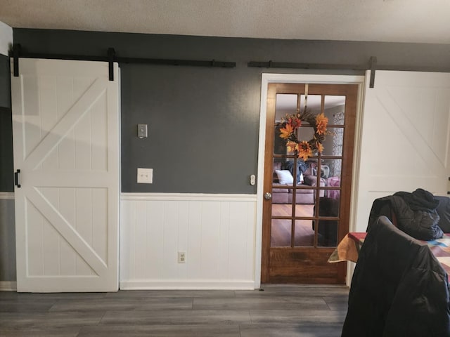 interior space with a barn door, dark wood-type flooring, and a textured ceiling