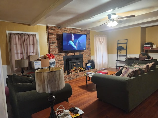 living room with beamed ceiling, hardwood / wood-style floors, a wood stove, and ceiling fan