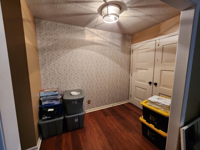 miscellaneous room featuring dark wood-type flooring and a textured ceiling