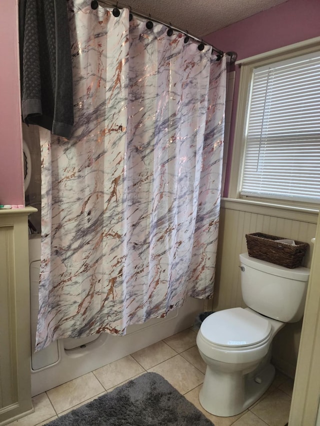 bathroom featuring tile patterned floors, toilet, a textured ceiling, and shower / tub combo