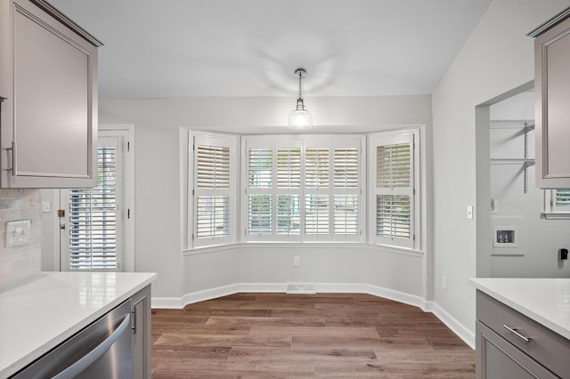 kitchen with wood-type flooring, stainless steel dishwasher, decorative backsplash, and decorative light fixtures