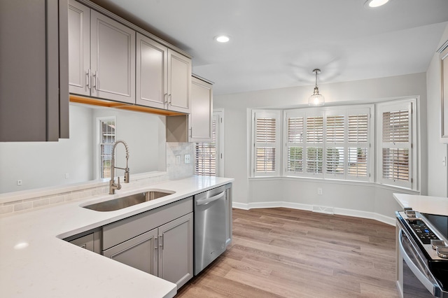 kitchen featuring sink, gray cabinets, appliances with stainless steel finishes, backsplash, and light hardwood / wood-style floors