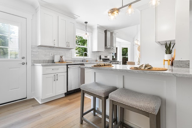 2020 Piper Dr, Charleston, SC 29407 - kitchen with appliances with stainless steel finishes, wall chimney range hood, light wood-type flooring, white cabinets, and decorative backsplash