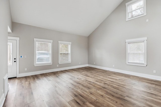 unfurnished living room with light hardwood / wood-style floors and high vaulted ceiling