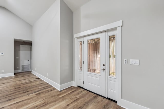 entrance foyer with high vaulted ceiling and light hardwood / wood-style flooring