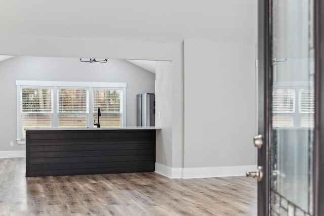 interior space featuring light wood-type flooring, sink, stainless steel fridge, and vaulted ceiling