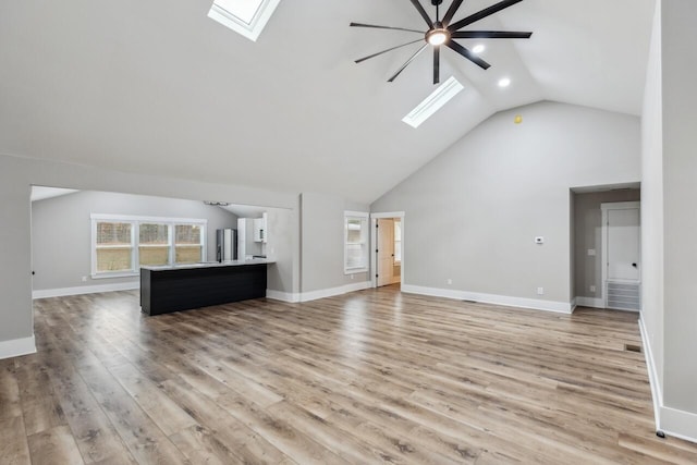 unfurnished living room with lofted ceiling with skylight, ceiling fan, and light hardwood / wood-style flooring