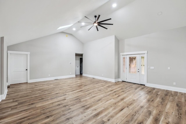 unfurnished living room featuring light hardwood / wood-style flooring, lofted ceiling with skylight, and ceiling fan