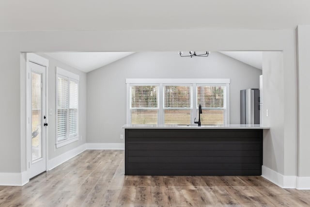 interior space featuring sink, vaulted ceiling, and light wood-type flooring