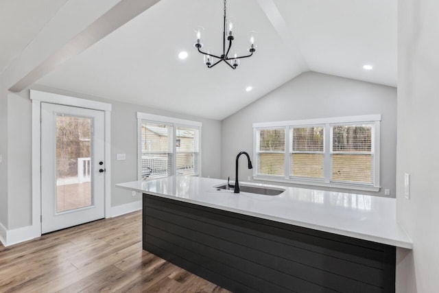 kitchen with pendant lighting, sink, an inviting chandelier, light hardwood / wood-style floors, and vaulted ceiling