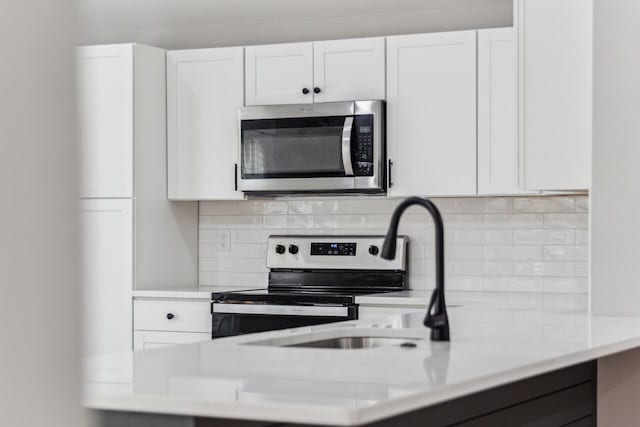 kitchen with range with electric stovetop, white cabinetry, sink, and decorative backsplash