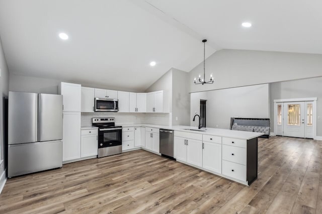 kitchen featuring white cabinetry, hanging light fixtures, stainless steel appliances, tasteful backsplash, and kitchen peninsula