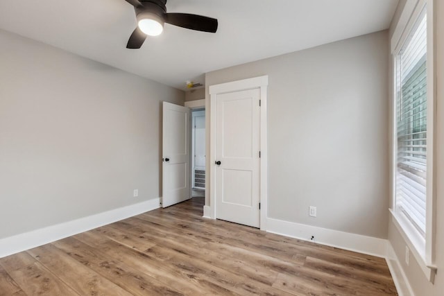 unfurnished bedroom with ceiling fan, multiple windows, and light wood-type flooring