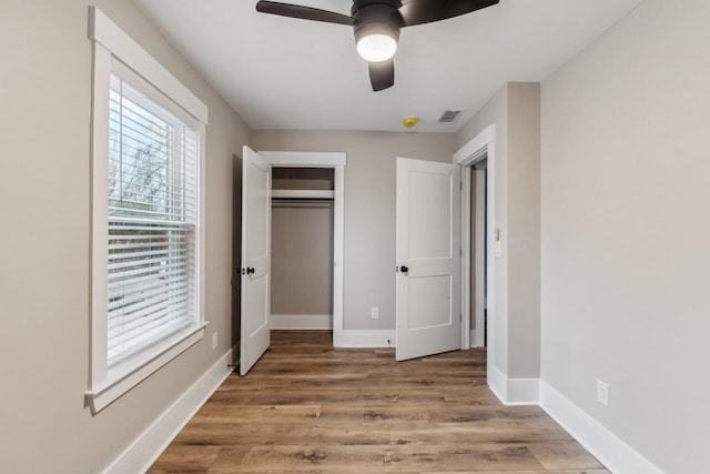 unfurnished bedroom featuring ceiling fan, a closet, and light wood-type flooring