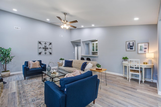 living room with light wood-type flooring, lofted ceiling, baseboards, and recessed lighting