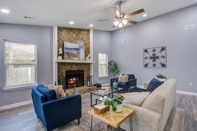 living room with a fireplace, wood finished floors, visible vents, and baseboards