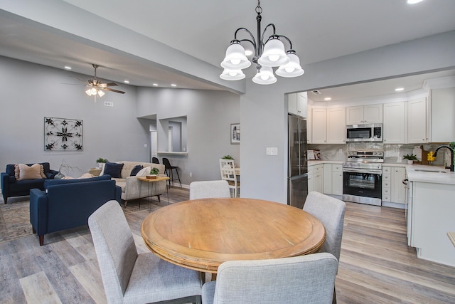 dining space with recessed lighting, vaulted ceiling, light wood-style flooring, and ceiling fan with notable chandelier