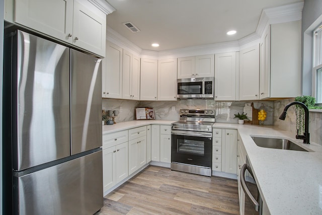 kitchen with light wood finished floors, visible vents, appliances with stainless steel finishes, white cabinetry, and a sink