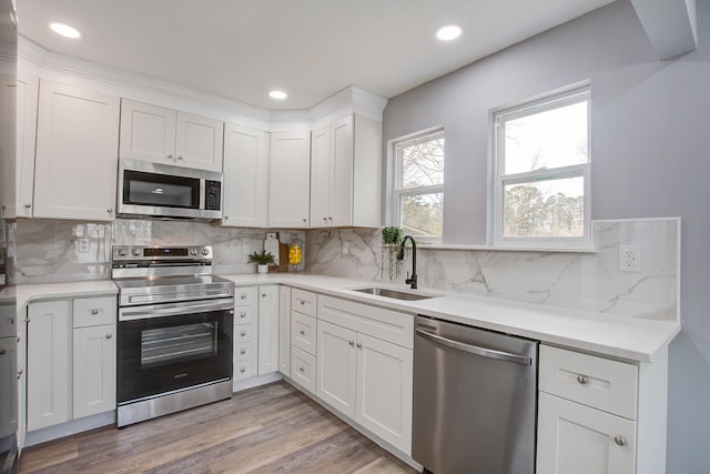 kitchen with recessed lighting, stainless steel appliances, a sink, white cabinetry, and light wood-type flooring