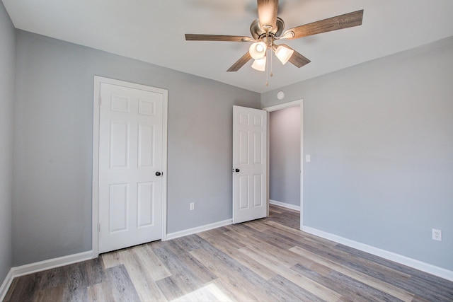 unfurnished bedroom with light wood finished floors, ceiling fan, and baseboards