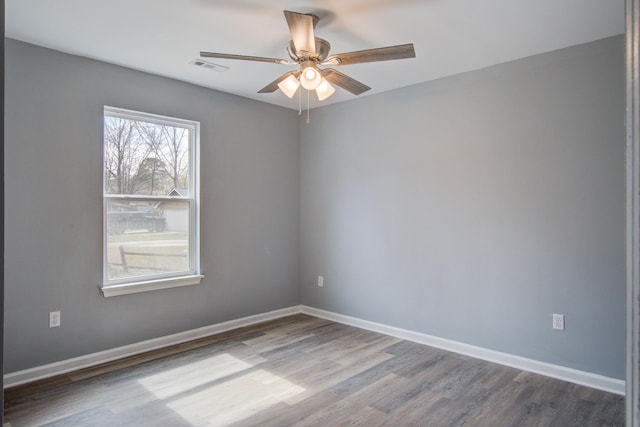 unfurnished room featuring baseboards, visible vents, ceiling fan, and wood finished floors