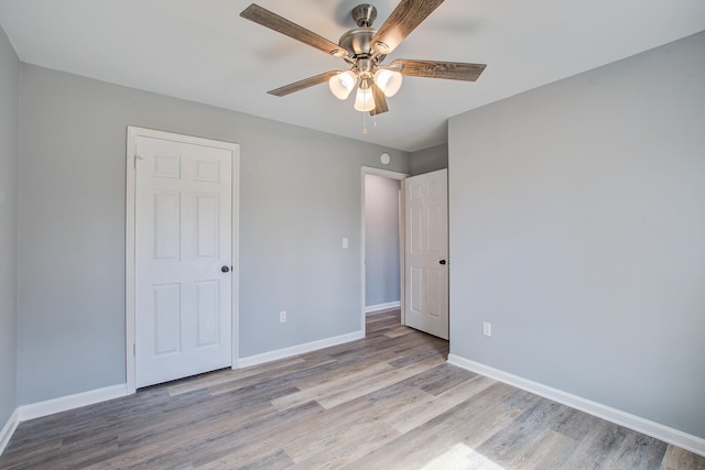 unfurnished bedroom featuring light wood-type flooring, baseboards, and a ceiling fan