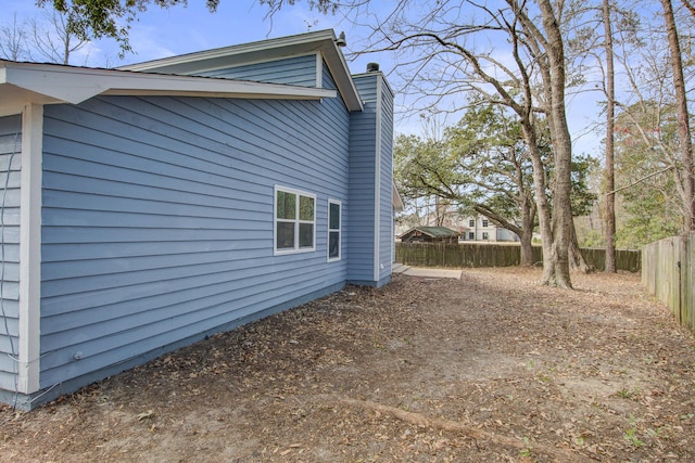 view of side of property featuring a chimney and fence