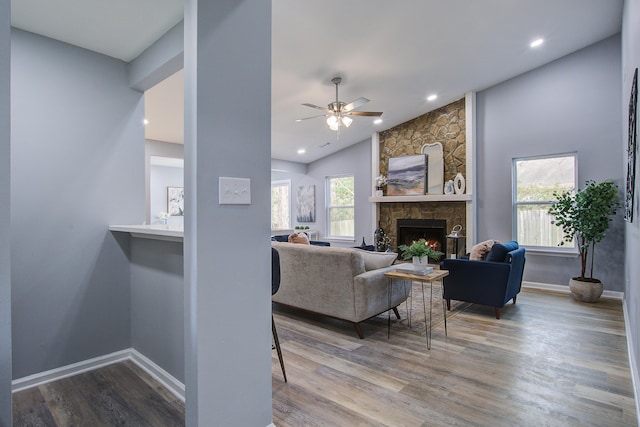 living room featuring recessed lighting, a stone fireplace, baseboards, and wood finished floors