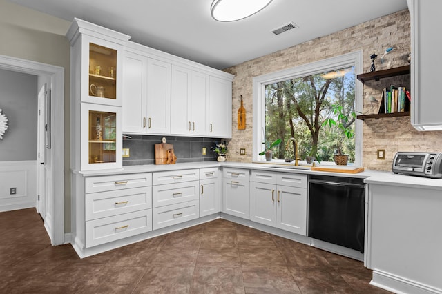 kitchen featuring tasteful backsplash, white cabinetry, black dishwasher, and sink