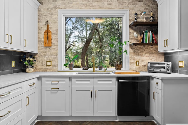 kitchen featuring sink, tasteful backsplash, light stone counters, black dishwasher, and white cabinets