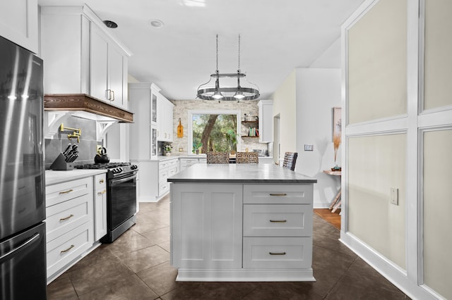 kitchen featuring pendant lighting, dark tile patterned floors, appliances with stainless steel finishes, white cabinets, and a kitchen island