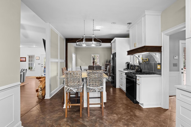 kitchen with white cabinetry, decorative light fixtures, a center island, a kitchen breakfast bar, and black appliances