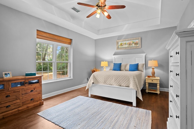 bedroom featuring dark hardwood / wood-style flooring, a raised ceiling, and ceiling fan